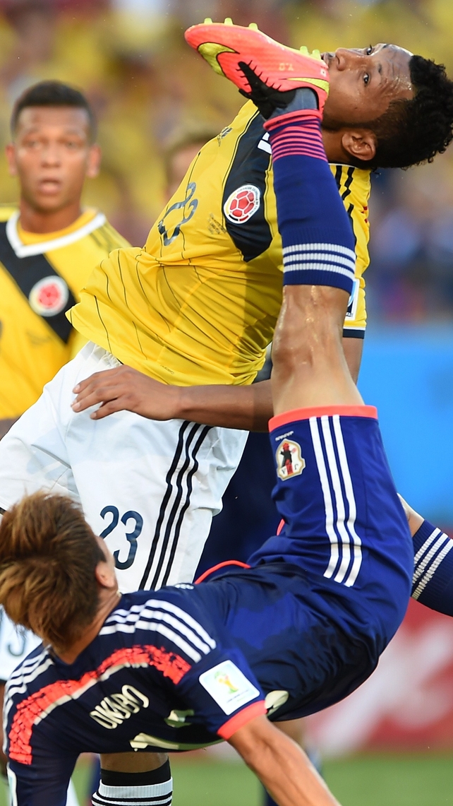Japan's Yoshito Okubo (bottom) and Colombia's Carlos Valdes contorting in contention for the ball