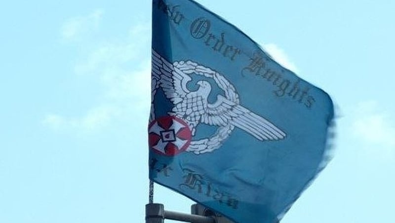 The flag features an Aryan eagle and red KKK symbol and bears the words New Order Knights and Ku Klux Klan