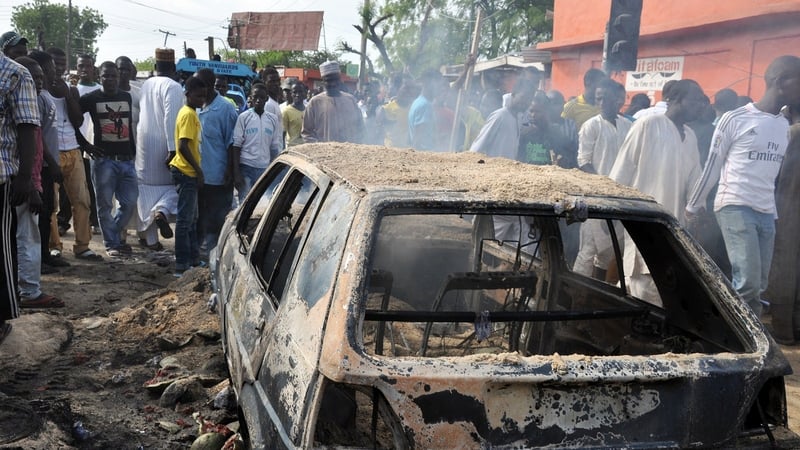 People gather around a burnt-out car following the explosion