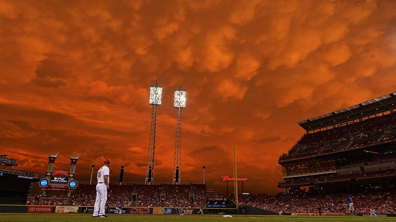 Storm clouds blanket the sky over Great American Ball Park as Starlin Castro #13 of the Chicago Cubs fields a ground ball in the fifth inning against the Cincinnati Reds