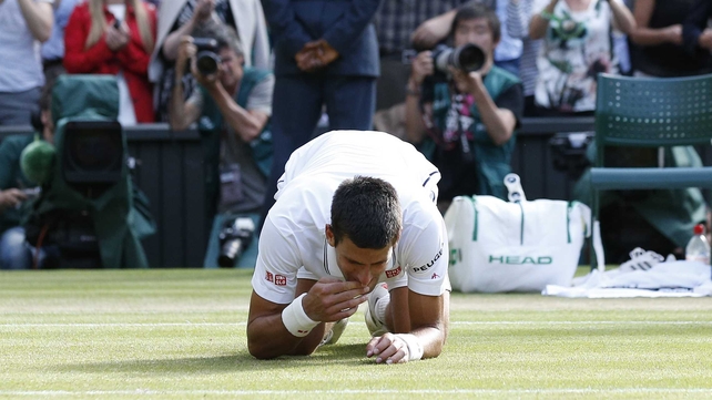 Novak Djokovic celebrates beating Roger Federer to win Wimbledon by eating the grass