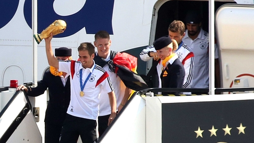 Germany's captain Philipp Lahm holds the World Cup aloft as he gets off an airplane at Berlin airport Tegel