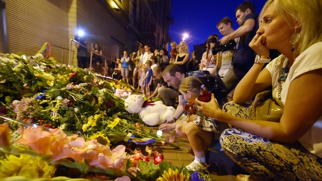 A woman looks at flowers and candles in front of the Embassy of the Netherlands in Kiev for the people who died on Flight MH17