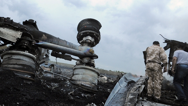 A man in military fatigues stands next to the wreckage of MH17