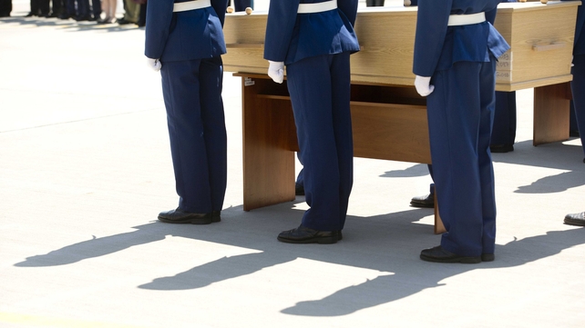 Ukrainian soldiers stand beside a wooden coffin on the tarmac at the airport in Kharkiv