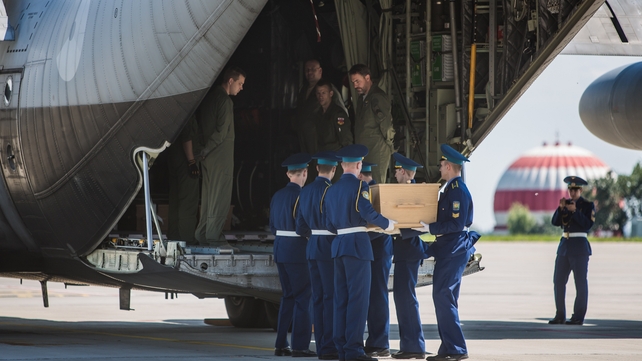 Soldiers load a coffin onto a military transport