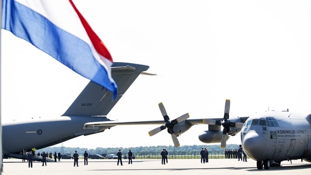 Dutch national flag flies at half-mast as the Dutch Air Force C-130 Hercules plane (R) and an Australian Royal Australian Air Force C17 transport plane arrive at Eindhoven