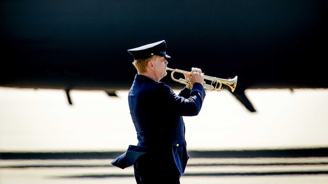A lone trumpeter plays the Last Post as the coffins are taken from the planes
