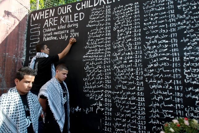 Palestinian youths list the names of the children who were killed in the ongoing conflict in Gaza