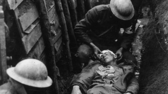 Red Cross workers in a trench tend to a wounded US soldier on a stretcher