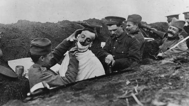 A soldier gets a shave in a Serbian trench