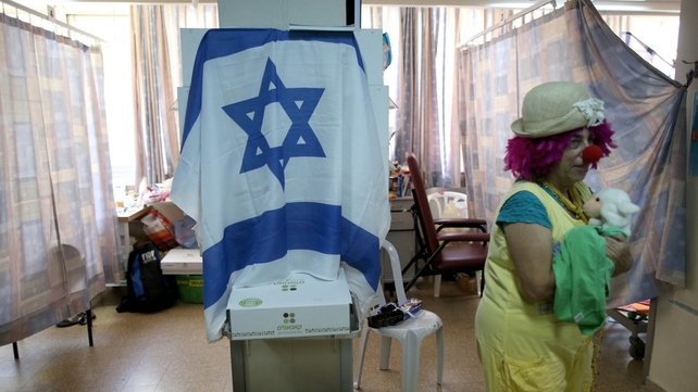 An Israeli woman dressed as a clown tries to cheer up an injured soldier at the same hospital
