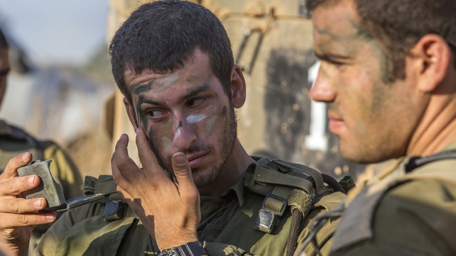 Israeli soldiers camouflage their faces at an army staging area before battle