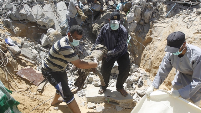 Rescue workers remove the body of a dead child from the rubble of the Duheir family home, which was destroyed in an Israeli air strike