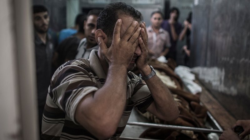 A Palestinian man reacts as he sees the body of a relative who died when a UN school used as a shelter was hit by Israeli shelling