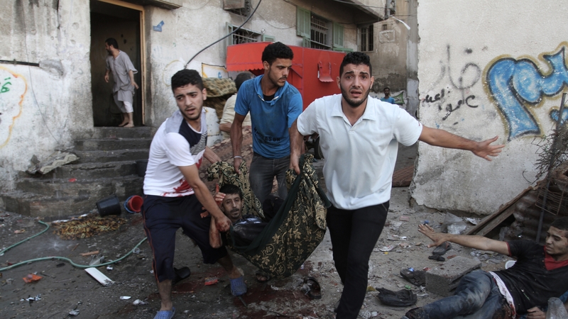 Palestinians carry a man who was wounded during an Israeli airstrike on a market place in the Shejaiya neighbourhood near Gaza City