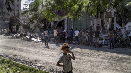 A Palestinian child covers her eyes to protect them from dust flying from a house hit by an Israeli military strike