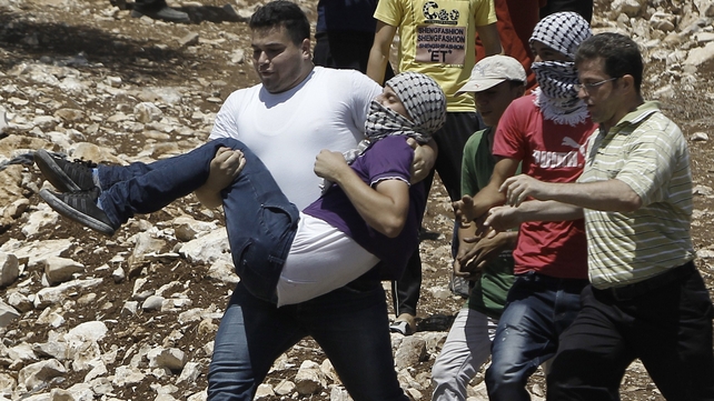 Palestinian protesters carry a fellow demonstrator injured during clashes with Israeli security forces in a protest in the village of Kfar Qaddum in the West Bank