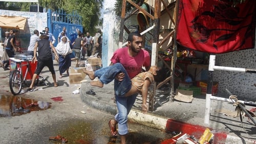 A Palestinian man carries an injured child following an Israeli military strike on a UN school in Rafah