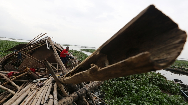 A Filipino resident emerges from a damaged home destroyed by a typhoon at a village in Taguig City, east of Manila, the Philippines