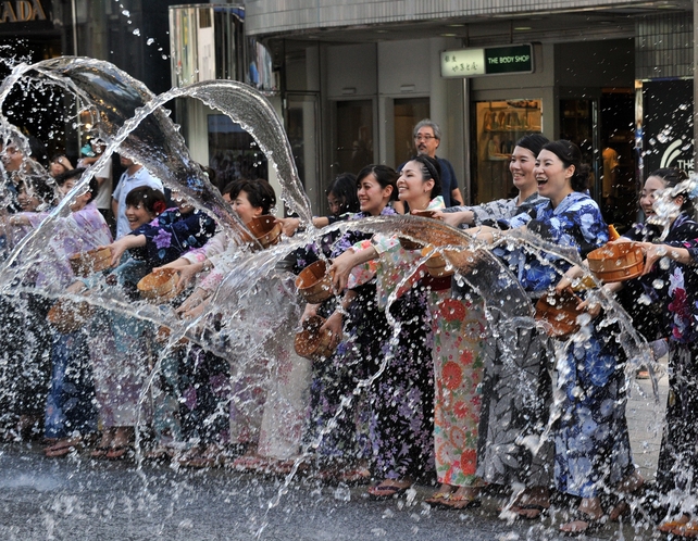 People dressed in 'yukatas', or cotton summer kimonos, splash water onto the ground along a street in the shopping area of Ginza in Tokyo. Hundreds of yukata-clad people participated in the annual summer event to cool off as temperatures soared over 35C