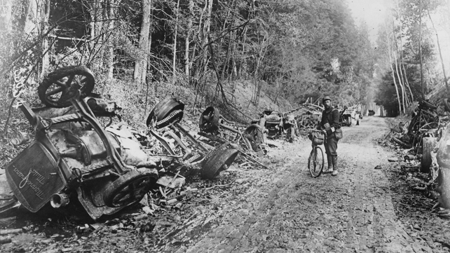 A lone soldier with a bicycle stands amid the remains of a German motor convoy which lines a country lane after an attack by French field guns in the battle of the Aisne in France