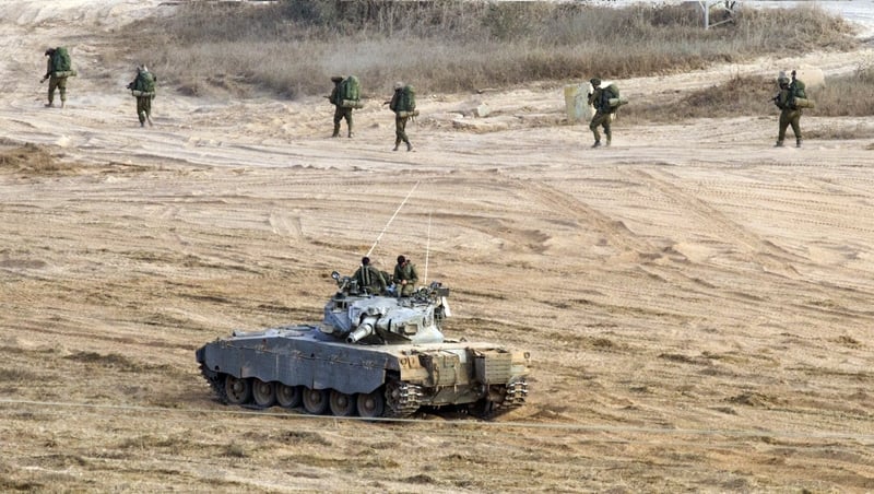 Israeli soldiers walk close to Israel's border with the Gaza Strip