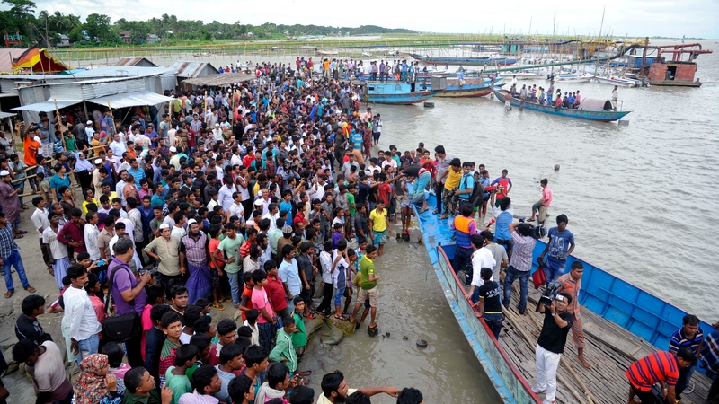 Local people and relatives gather at a beach after a ferry carrying capsized in the Padma River
