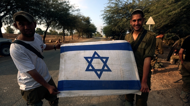 Israeli infantry soldiers hold an Israeli flag after they left Gaza