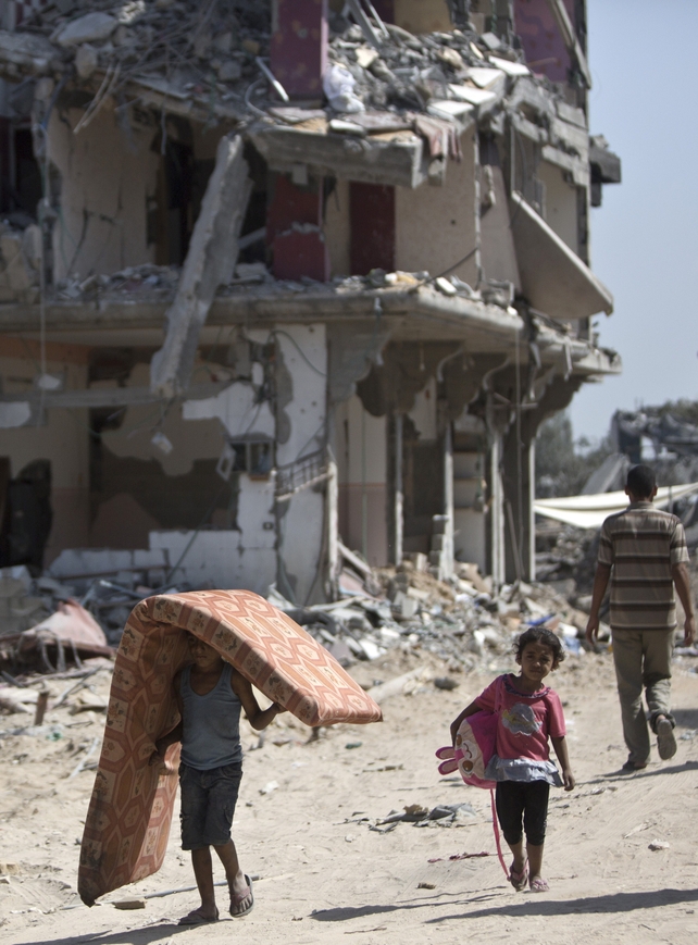 Palestinians salvage items from the rubble of destroyed buildings