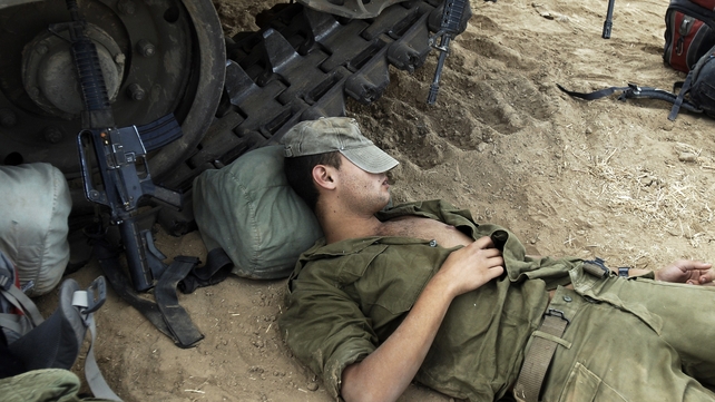 An Israeli soldier rests next to a tank at a new position a few kilometres from the Israel-Gaza border