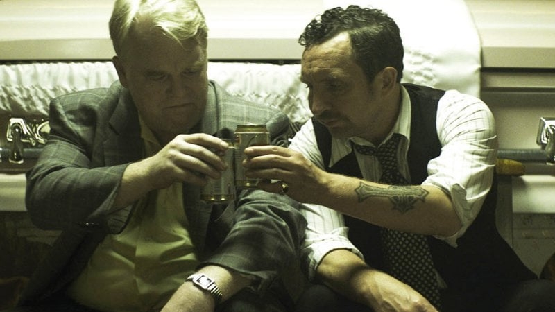 Sharing a drink by a coffin in God's Pocket. The late Philip Seymour Hoffman as Scarpato and Eddie Marsan as Smilin’ Jack Moran, the fiery undertaker.