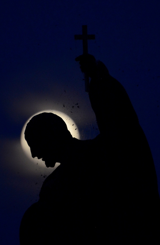 The full moon rises over the statue on the Charles Bridge in Prague