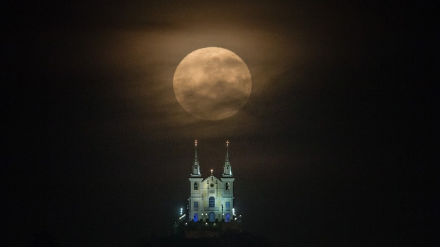 The supermoon descends behind the Nossa Senhora da Penha Church in Rio de Janeiro