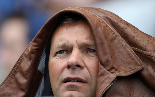 A supporter takes shelter under his coat during the heavy rain