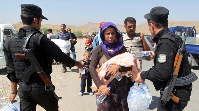 Peshmerga forces hand out water bottles to displaced Iraqi families from the Yazidi community