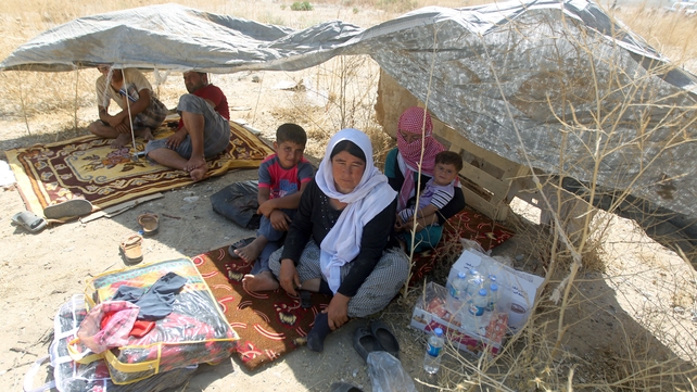 Displaced Iraqi families from the Yazidi community shelter from the blistering sun as they cross the Iraqi-Syrian border at the Fishkhabur crossing