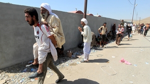 A man carries an elderly man as they wait to cross the border at the Fishkhabur crossing