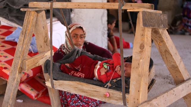 A woman sits next to a baby as they shelter inside a building under construction in the Kurdish city of Dohuk