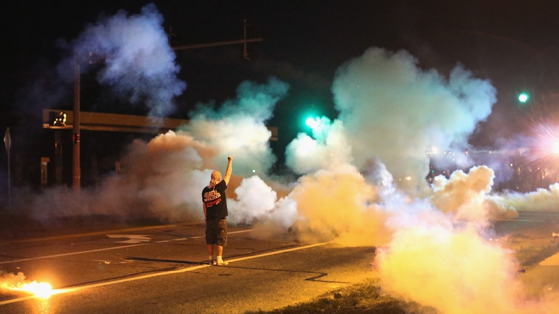 A demonstrator stands his ground as police fire tear gas