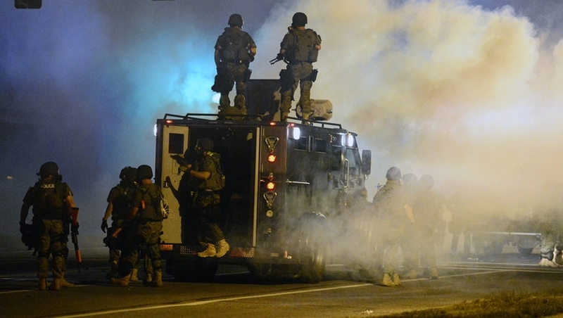 Police officers stand guard as demonstrators protest the shooting death of Michael Brown in Ferguson