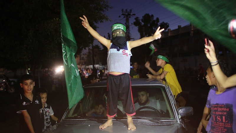 A Palestinian child wearing a Hamas headband celebrates the truce by flashing the victory sign in Rafah in Gaza