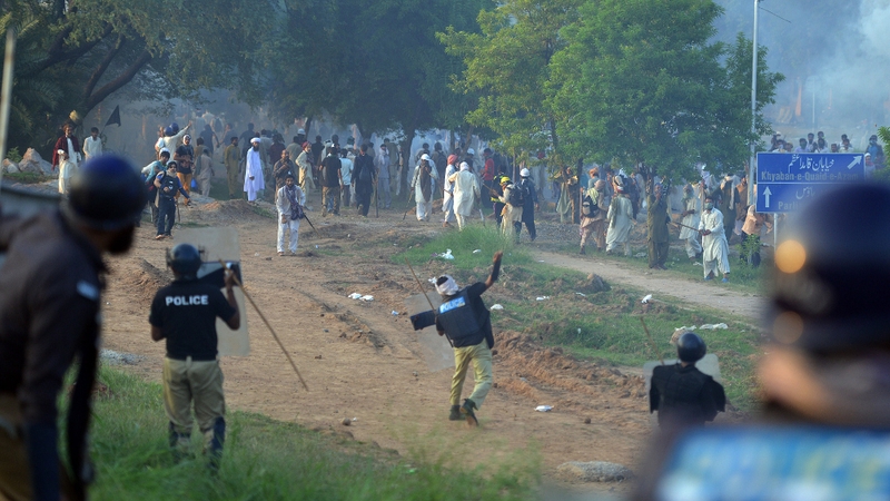 Pakistani riot police throw stones towards protesters following clashes with security forces near the prime minister's residence