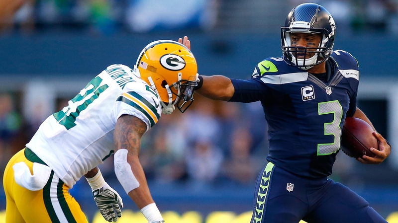 Seattle quaterback Russell Wilson (R) escapes the tackle attempt of Green Bay Packers' safety Ha Ha Clinton-Dix