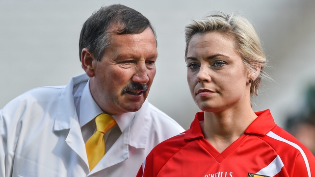 Umpire Mark Dunne, from the Moyne Templetuohy club, speaks with Cork captain Anna Geary before the senior game