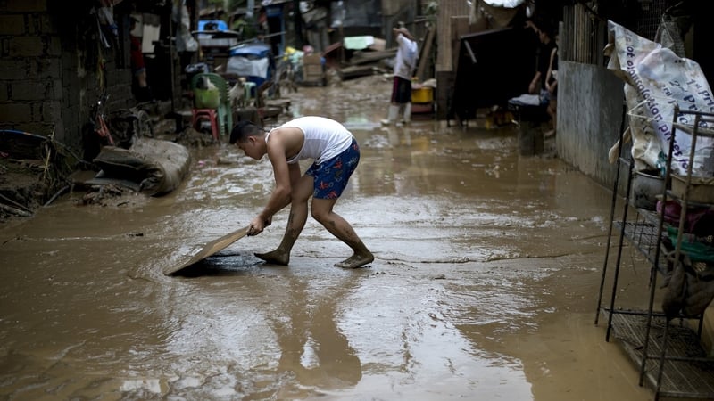 A man clears mud form his house in a suburb of Manila in the aftermath of the storm