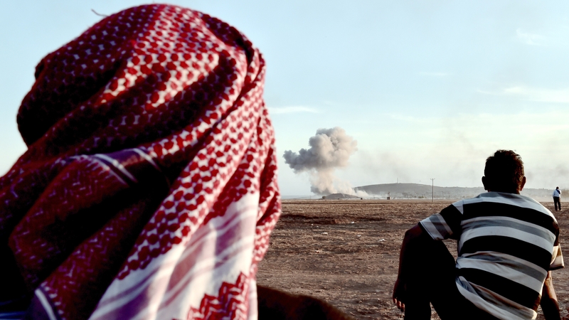 People watch smoke rising from the Syrian town of Kobane after an air strike