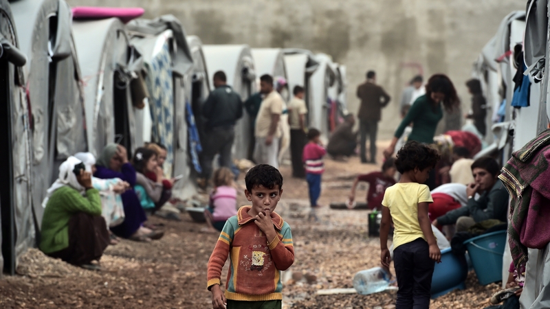 A boy walks past tents at a Syrian Kurdish refugee camp in the Turkish town of Suruc