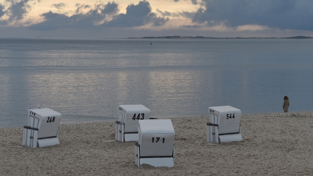 A woman stands at the North Sea beach of Hoernum on the island of Sylt, northwestern Germany
