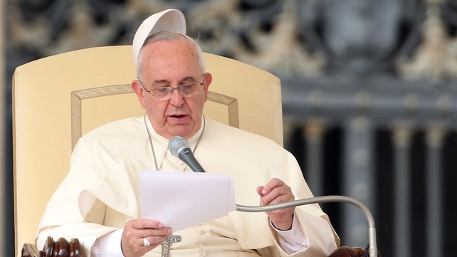 The biretta cup of Pope Francis is blown over his head as he holds his weekly audience in St Peter's Square